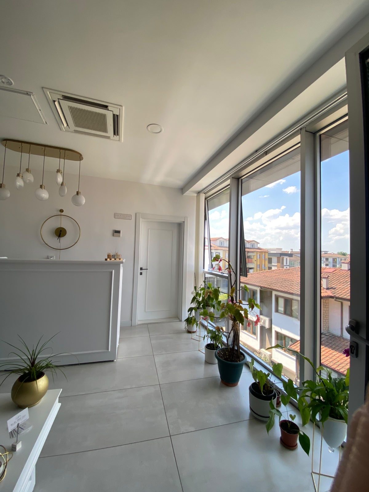 Klinik resepsiyon bankosu ve geniş pencereden aydınlık manzara